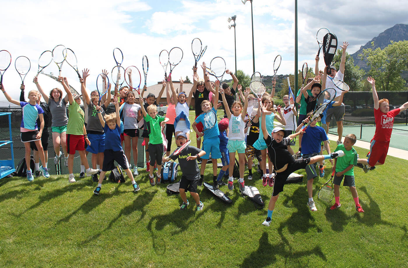 kids posing with raised tennis racquets