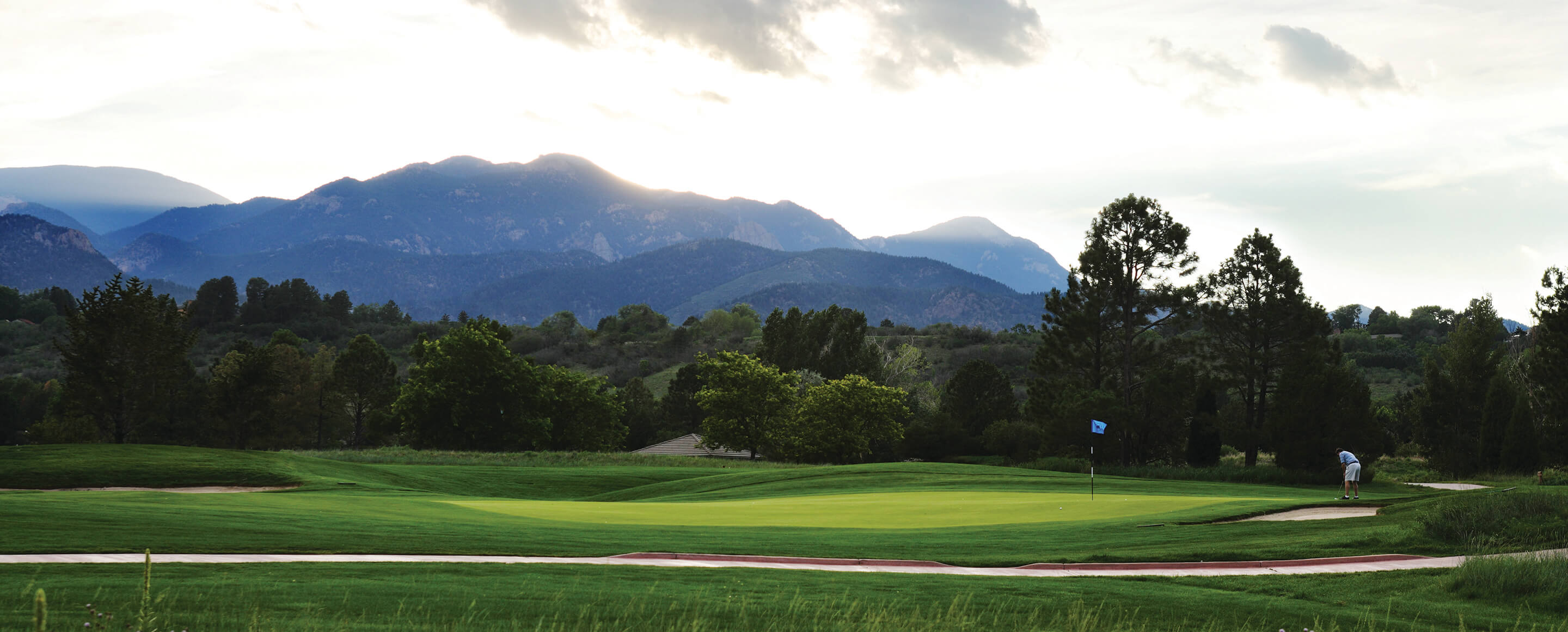 golfer on green with hills and mountains in background